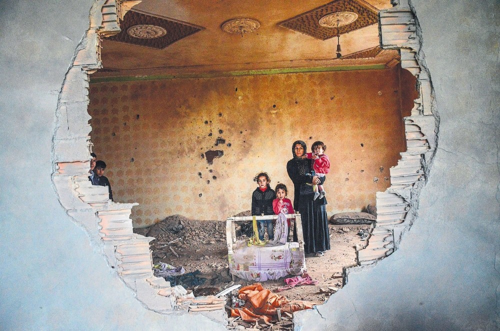 A woman and her children stand in the ruins of a house damaged by PKK terrorists clashing with security forces in the predominantly Kurdish town of Silopi, southeastern Turkey, January 19, 2016.