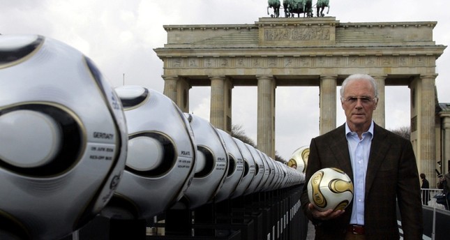 فرانز بيكنباور، رئيس اللجنة المنظمة لكأس العالم في ألمانيا، يحمل كرة قدم ذهبية خلال عرض تقديمي بجوار بوابة براندنبورغ. برلين في 18 أبريل 2006 رويترز