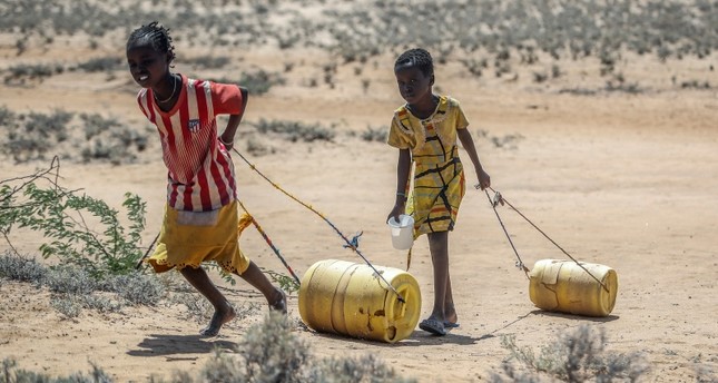 فتيات صغيرات يسحبن حاويات من الماء أثناء عودتهن إلى أكواخهن من بئر في قرية لوموبوث في شمال كينيا AP