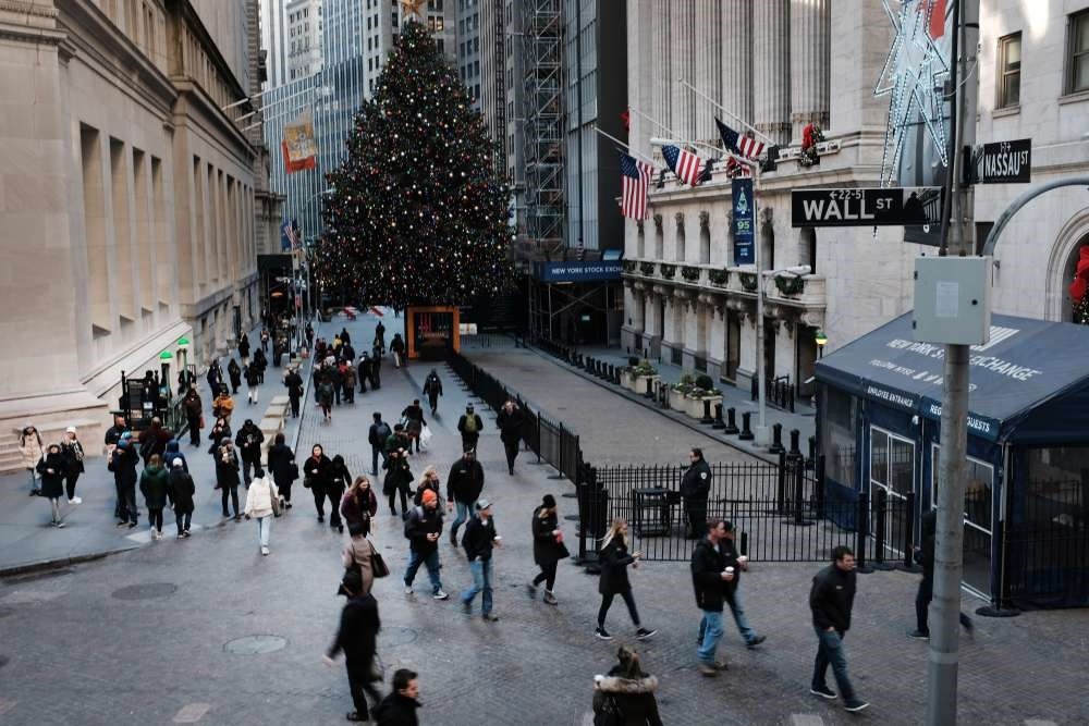 People walk by the New York Stock Exchange (NYSE) and the NYSE Christmas Tree in New York City, Dec. 17.