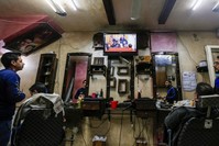 Palestinians watch the televised press conference of U.S. President Donald Trump and Israeli Prime Minister Benjamin Netanyahu at a barber shop in Gaza City, Jan. 28, 2020. (AFP Photo)