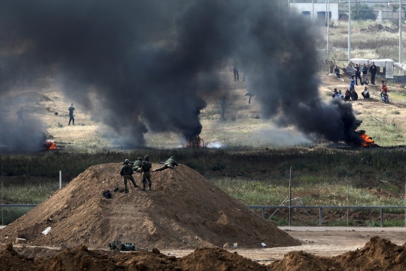 Israeli soldiers are seen next to the border fence on the Israeli side of the Israel-Gaza border, as Palestinians protest on the Gaza side of the border, Israel April 5, 2018. (Reuters Photo)