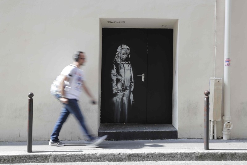 In this file photo taken on June 25, 2018 A man walks past an artwork by street artist Banksy in Paris on a side street to the Bataclan concert hall where a terrorist attack killed 90 people on Novembre 13, 2015. (AFP Photo)