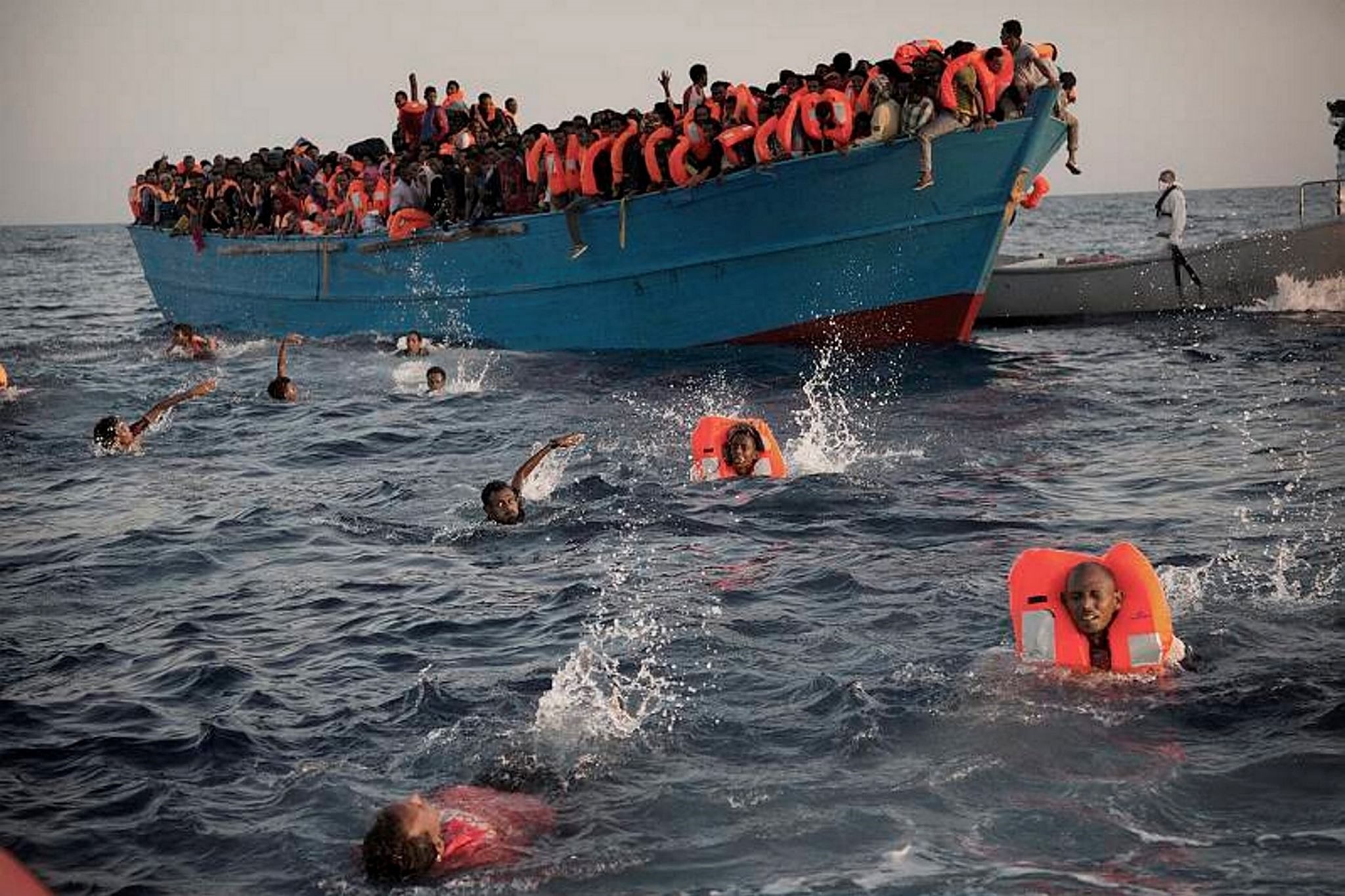 Migrants, mostly Eritrea, jump into the water from a crowded wooden boat as they are helped by members of an NGO during a rescue operation on the Mediterranean, about 21 kilometers north of Sabratha, Libya.