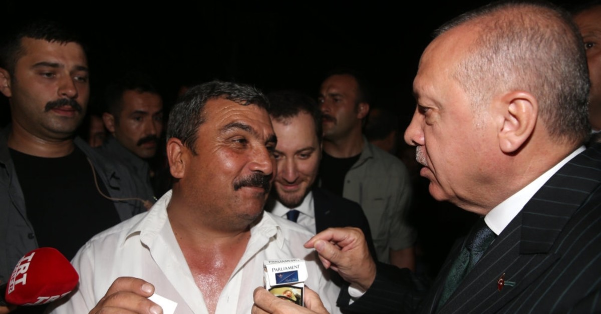 President Recep Tayyip Erdou011fan takes a supporter's pack of cigarette as he tries to convince him to quit smoking, Istanbul, June 25, 2019.