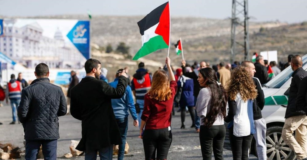 Palestinians wave the national flag as they protest a US peace plan proposal, at the northern entrance of the West Bank city of Ramallah, Jan. 30, 2020. (AFP Photo)