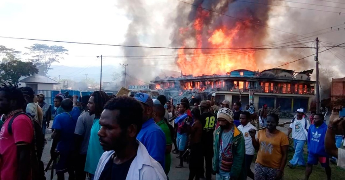 People gather as shops burn in the background during a protest in Wamena in Papua province, Indonesia, Monday, Sept 23, 2019. (AP Photo)