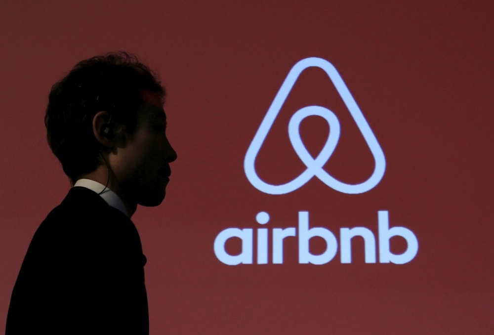 A man walks past a logo of Airbnb after a news conference in Tokyo.