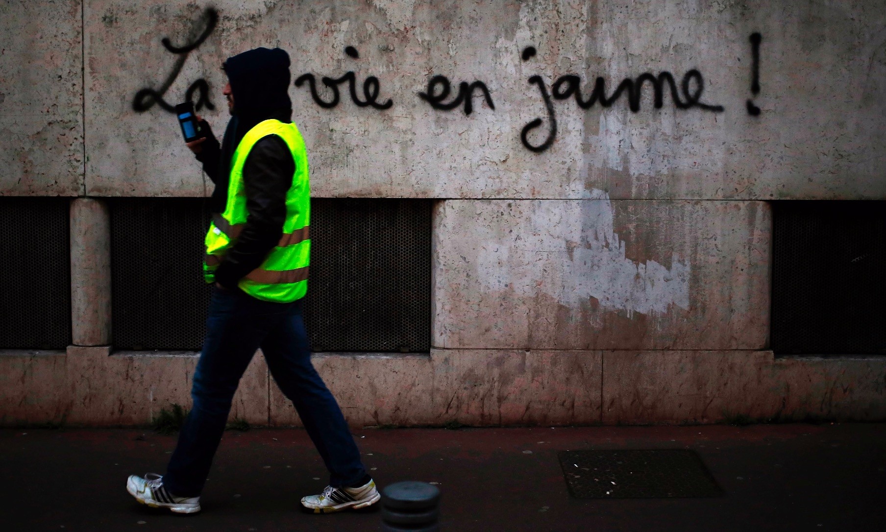 A man walks along a wall with the inscription u201cLife in yellowu201d during a demonstration of u201cyellow vestu201d (gilets jaunes) protesters, Rouen, Jan. 5.