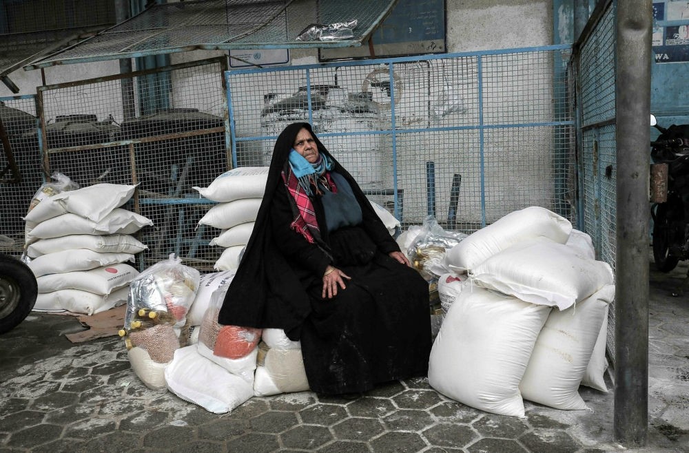 A Palestinian woman sits on a pile of food donations at a U.N. food distribution center in Khan Yunis, Gaza Strip, Jan. 28.