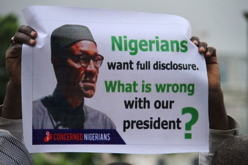 A protester shows a placard in the rain during a protest to demand that President Mohammadu Buhari resume work or resign in Abuja, on August 7, 2017.