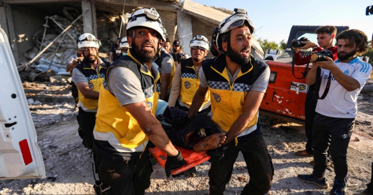 Members of ,White Helmets, carry away a body on a stretcher following a reported government air strike in the village of Benin, about 30 kilometers south of Idlib in northwestern Syria, on June 19, 2019. (AFP Photo)