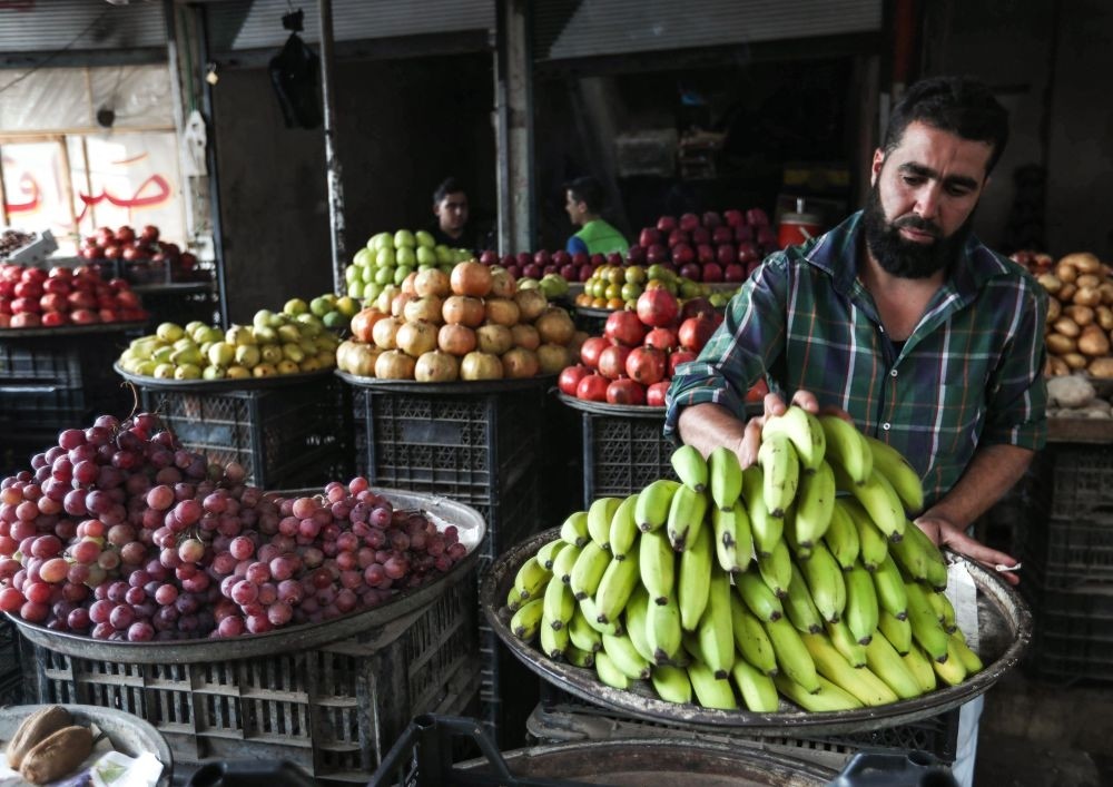 A Syrian fruit merchant organizes bananas outside his shop in the opposition-held town of Maaret al-Numan, just south of Idlib province, Sept. 27.