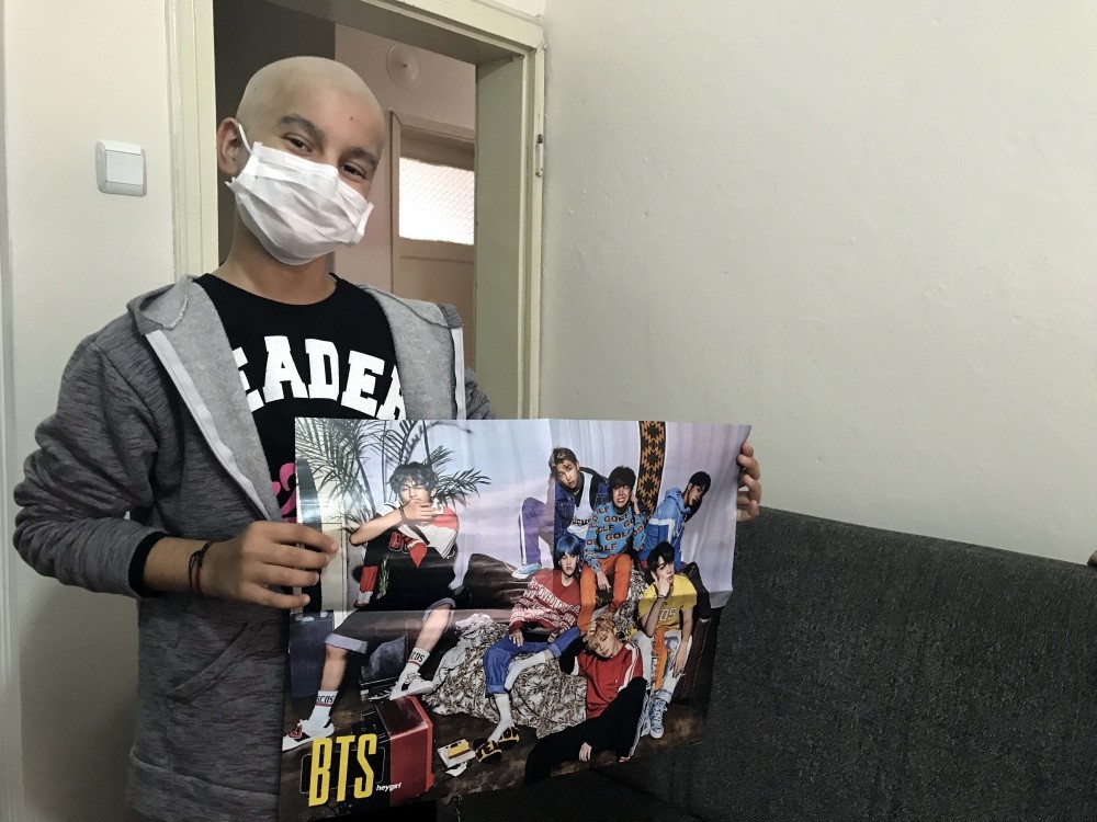 Havin Ayu015fe Baldaz holds a poster of her favorite band BTS.