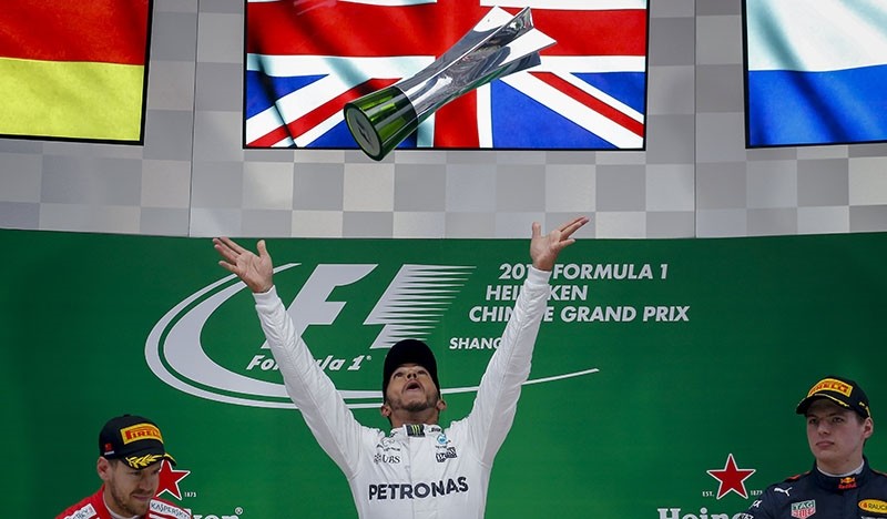British driver Lewis Hamilton (C) of Mercedes AMG GP throws his first place trophy in the air after winning the 2017 Chinese  Grand Prix, next to runner-up Sebastian Vettel (L) of Scuderia Ferrari and Max Verstappen of Red Bull Racing. (EPA Photo)