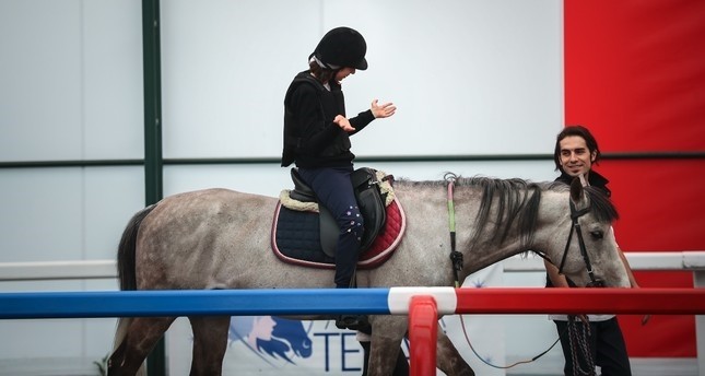 A disabled child enjoys riding a horse at the Horse Therapy Center in Veliefendi Hippodrome, Istanbul.