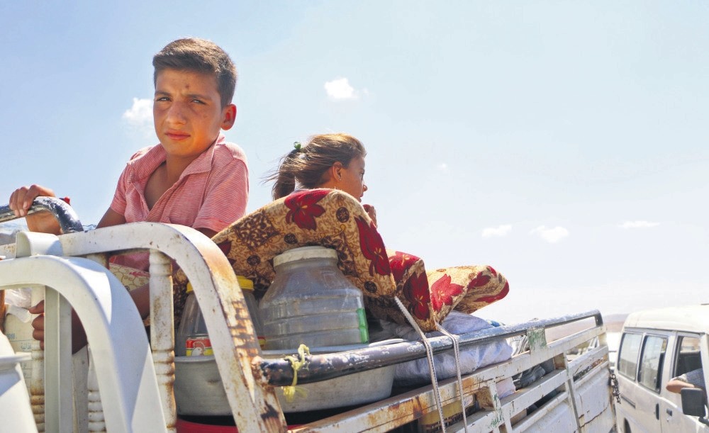 Syrians ride with their belongings in a pickup truck as they head to safer areas in Syria's Idlib province after fleeing regime attacks, Sept. 6.