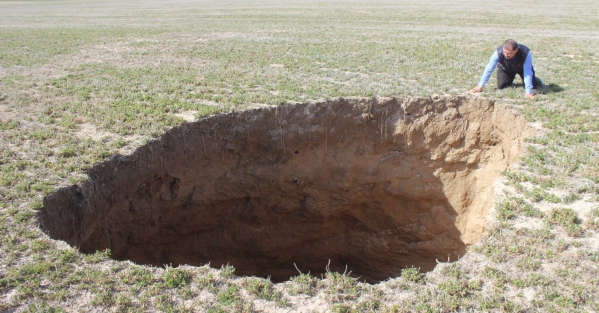 A man looks at a 10-meter-deep sinkhole in the middle of a field in Reu015fadiye village of Konya, Feb. 20, 2019.