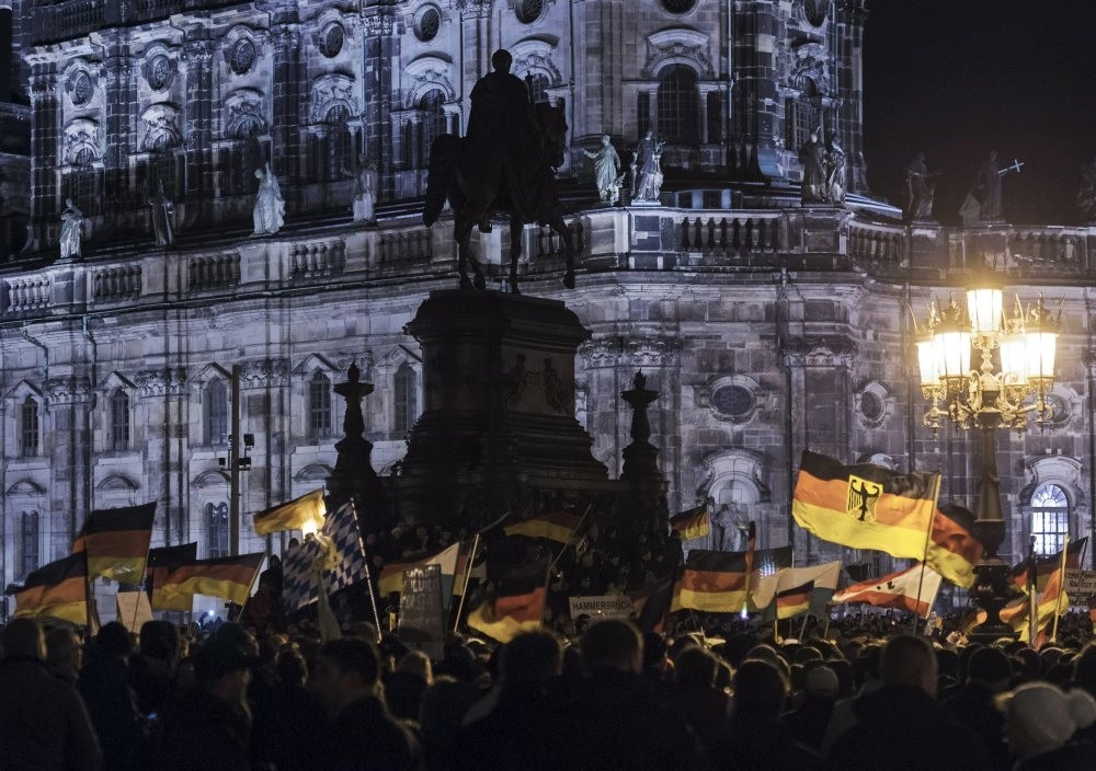 Pegida supporters, a German extremist, racist and Islamophobic group, hold German flags during a demonstration in front of the bronze equestrian statue of King John of Saxony, Dresden, Germany, Dec. 22, 2014. 