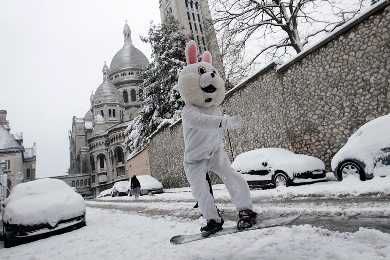 A man wearing a rabbit mask rides his snowboard down the Montmartre hill, with the Sacre Coeur Basilica in background, Wednesday, Feb.7, 2018 in Paris. (AP Photo)