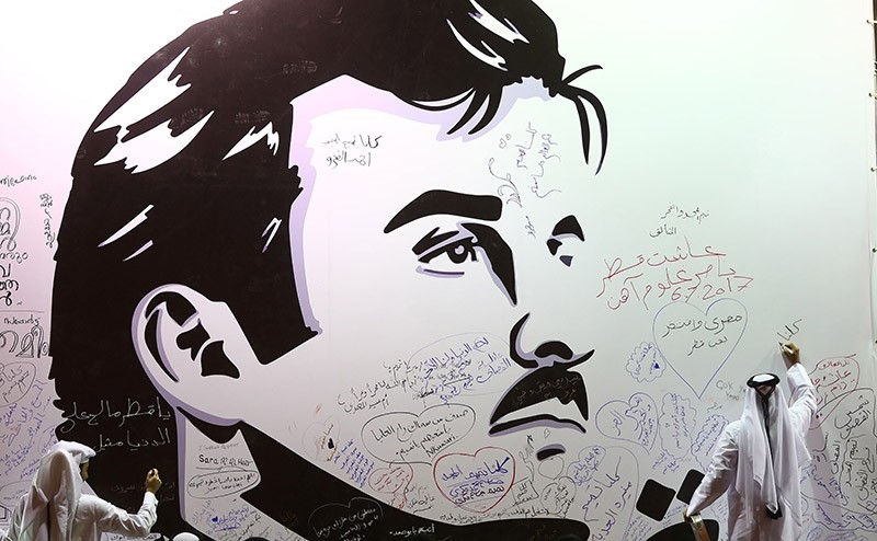 This file photo taken on July 6, 2017 in the Qatari capital Doha shows a man writing comments on a wall bearing portrait of Emir Sheikh Tamim bin Hamad Al Thani, which became symbol of resistance during the month-long Gulf crisis. (AFP Photo)