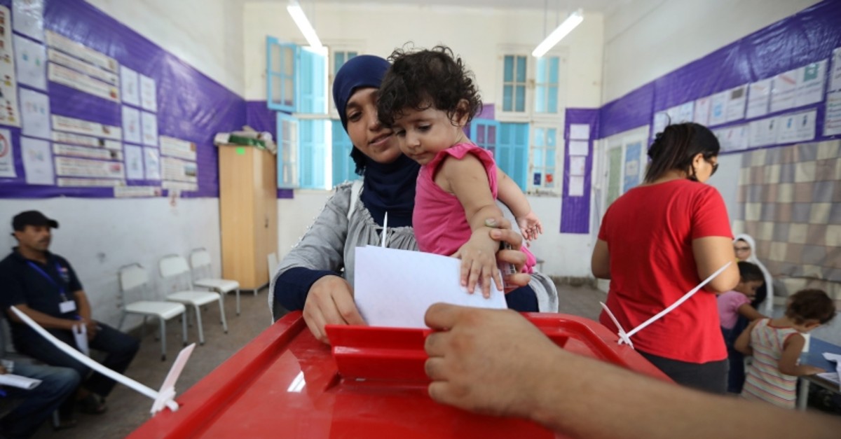 A woman carries a child as she casts her vote at a polling station during presidential election in Tunis, Tunisia Sept. 15, 2019. (Reuters Photo)