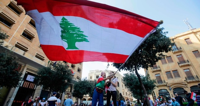 متظاهرون يرفعون العلم اللبناني في اكتوبر 2019 الفرنسية