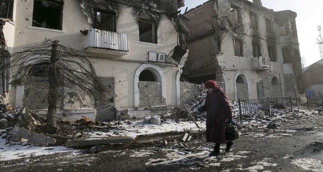 A woman walks past a damaged building in the town of Vuhlehirsk, Donetsk, Feb. 14, 2015. (REUTERS Photo)