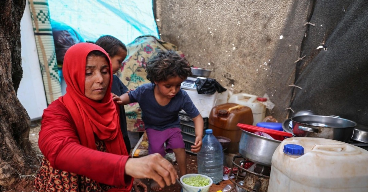 Mona Mutayr, a displaced Syrian mother, prepares an iftar meal in a field near a camp for displaced people in the village of Atme, near the Turkish border, May 23, 2019.