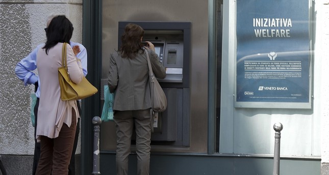 People line up at a cash machine of a Veneto Banca branch in Milan, Italy, Monday, June 26, 2017. (AP Photo)