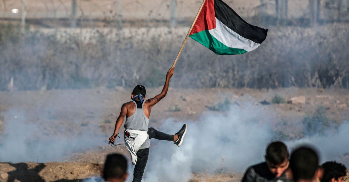 A protester raises a Palestinian flag during border protests, Gaza Strip, Sept. 6, 2019.
