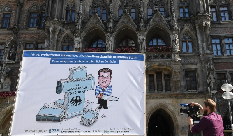 A cameraman films a banner depicting Bavaria's State Premier Markus Soeder who saws an edition of the German constitutional law into a cross during a protest rally against a new decree in Bavaria, Germany, on June 1, 2018. (AFP Photo)
