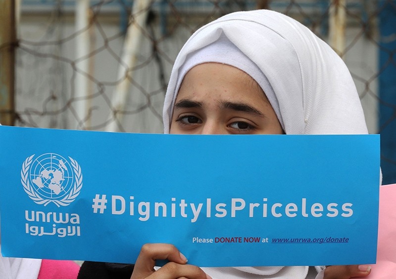 A Palestinian refugee holds a placard at a school belonging to the United Nations Relief and Works Agency for Palestinian Refugees (UNRWA) in Sebline, Lebanon, March 12, 2018. (AFP Photo)