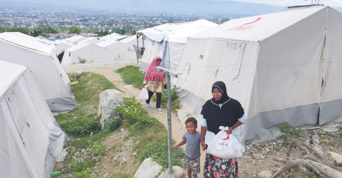 A woman carrying a bag with humanitarian aid at a tent camp in Palu, Indonesia, July 5, 2019.
