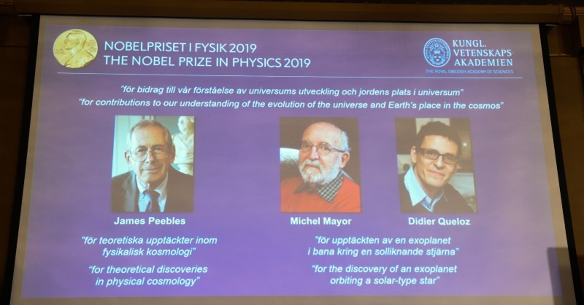 A screen displays the portraits of the laureats of the 2019 Nobel Prize in Physics (AFP Photo)