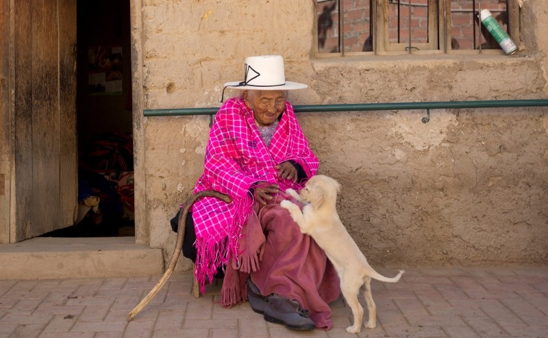 In this Aug. 23, 2018 photo, 117-year-old Julia Flores Colque plays with ,Chiquita,, one of the family pet dogs, while sitting outside her home in Sacaba, Bolivia. (AP Photo)