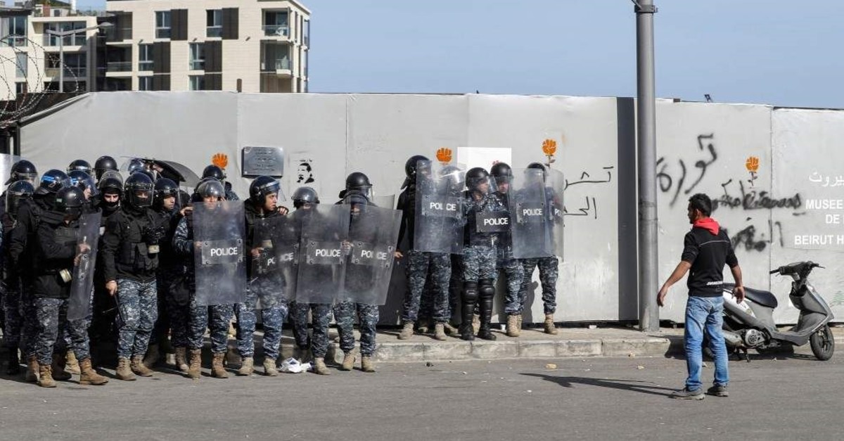 An anti-government protester stands before Lebanese riot police during clashes, Beirut, Jan. 27, 2020. (AFP Photo)