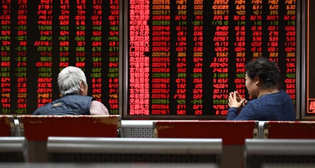 Two women sit in front of screens showing stock prices at a securities company in Beijing on January 21, 2019. (AFP Photo)