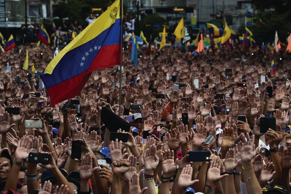 People raise their hands during a mass opposition rally against President Nicolas Maduro, in Caracas, Jan. 23. 
