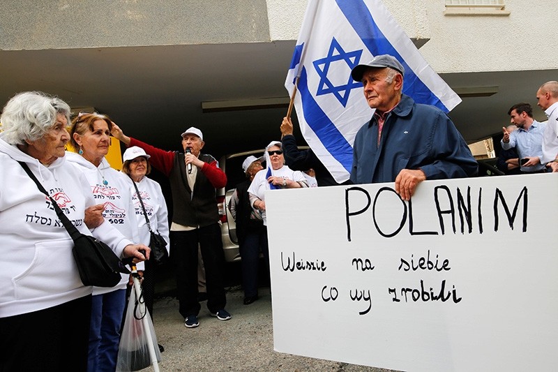Holocaust survivors hold banners and wave an Israeli flag during a protest in front of Polish embassy in Tel Aviv on February 8, 2018, against a controversial bill passed by the eastern European country's senate. (AFP Photo)