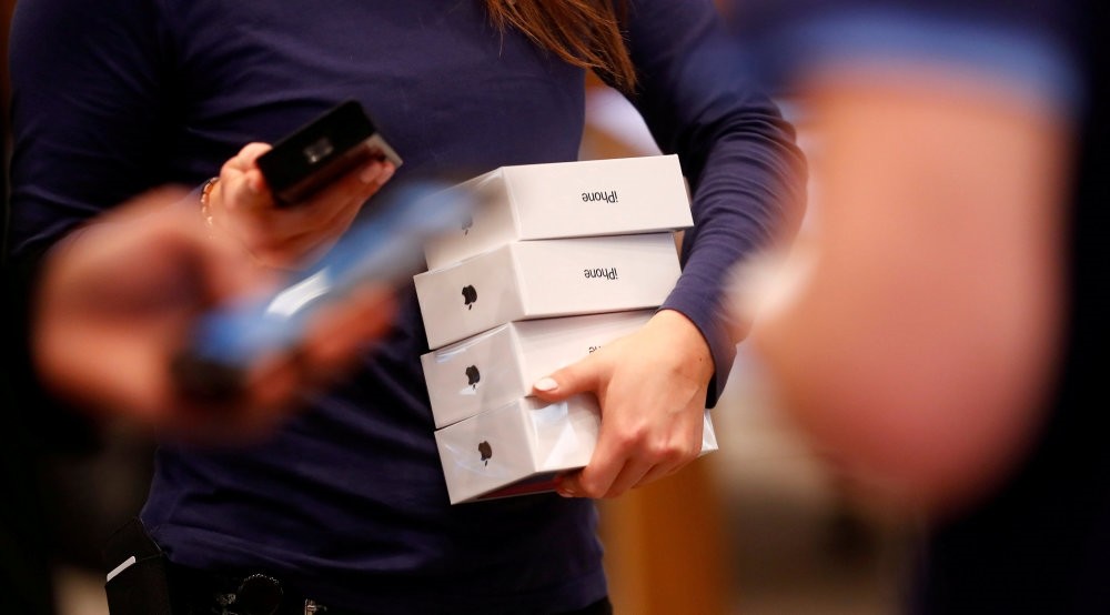 An Apple staff member holds iPhone X packages at the Apple Store in Berlin, Germany, Nov. 3, 2017.