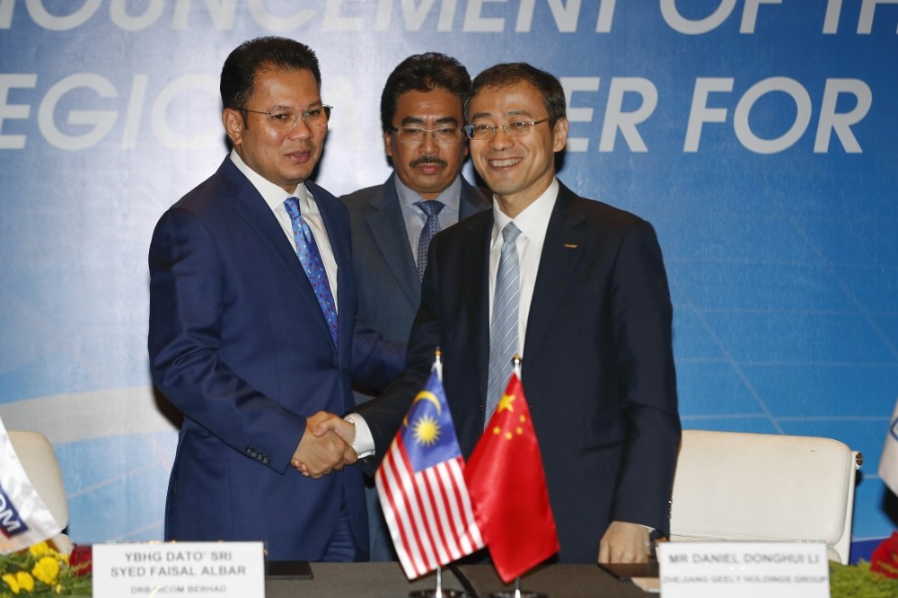 Protonu2019s owner DRB-Hicom Group Director Khalid Abdol Rahman, (L), and Geely Holding Group Chief Financial Officer Daniel Li, (R),shake hands as Malaysian Second Finance Minister Johari Abdul Ghani witnesses during a singing ceremony in Putrajaya.
