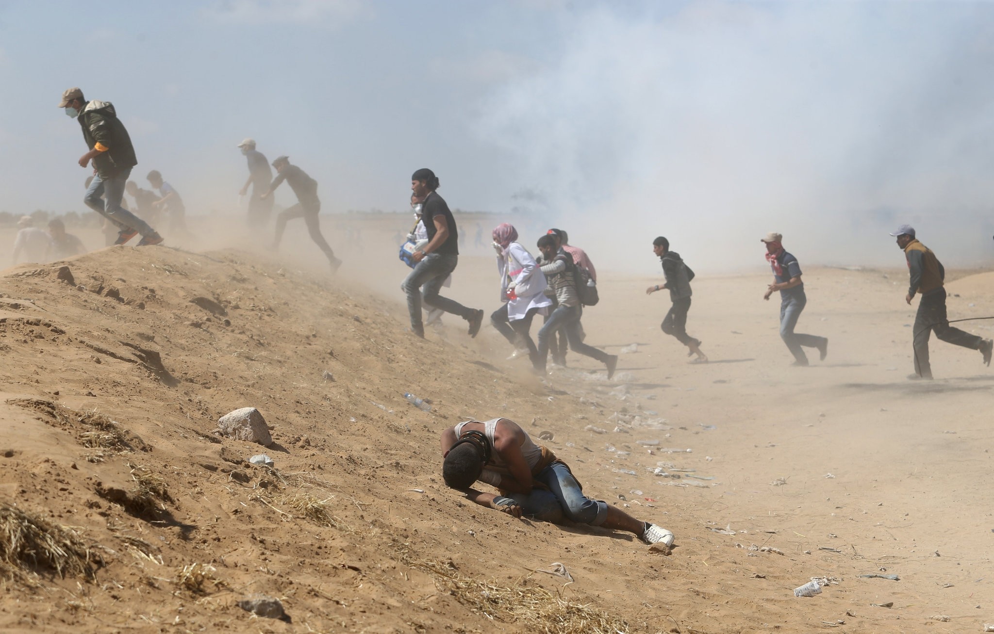 A Palestinian demonstrator reacts as others run from tear gas fired by Israeli forces during a protest marking the 70th anniversary of Nakba, at the Israel-Gaza border in the southern Gaza Strip yesterday.