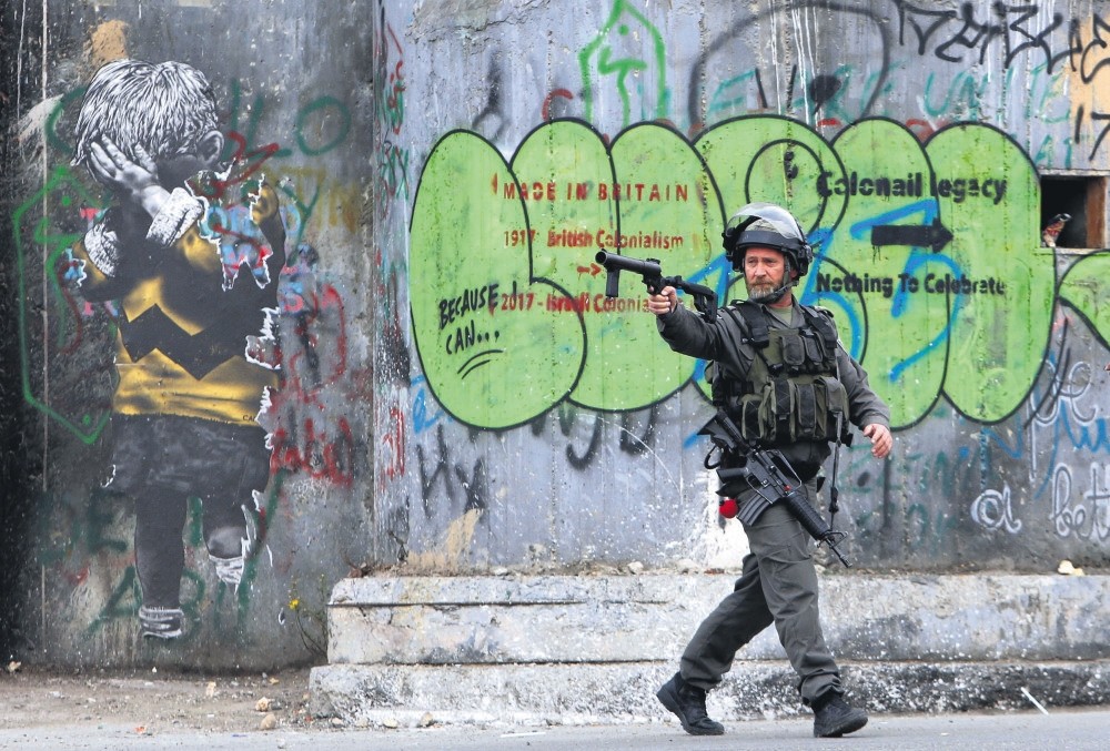 An Israeli border policeman aims his weapon during clashes with Palestinians during a protest against President Trump's decision to recognize Jerusalem as the capital of Israel, Bethlehem, West Bank, Dec. 20. 