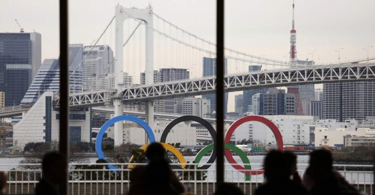 People dine in a hotel restaurant as the Olympic rings float in the water near the Rainbow Bridge in Tokyo, Jan. 17, 2020. (AP Photo)