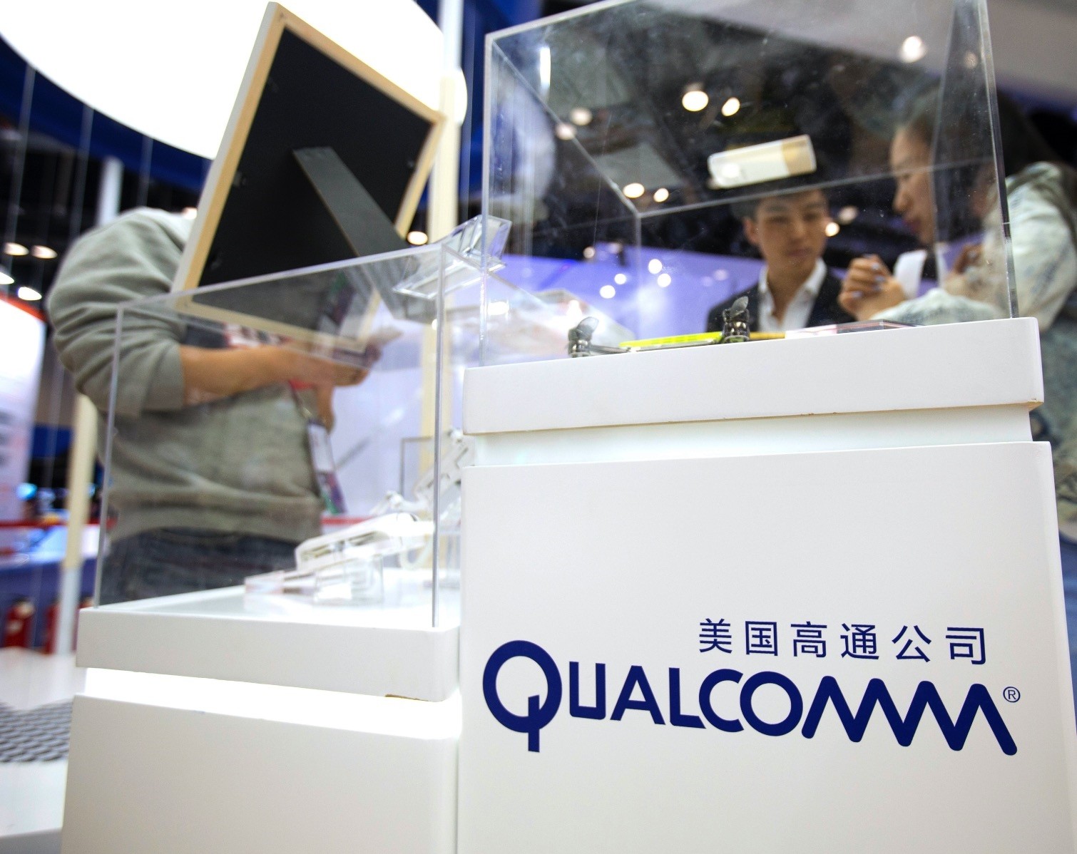 Visitors look at a display booth for Qualcomm at the Global Mobile Internet Conference in Beijing.