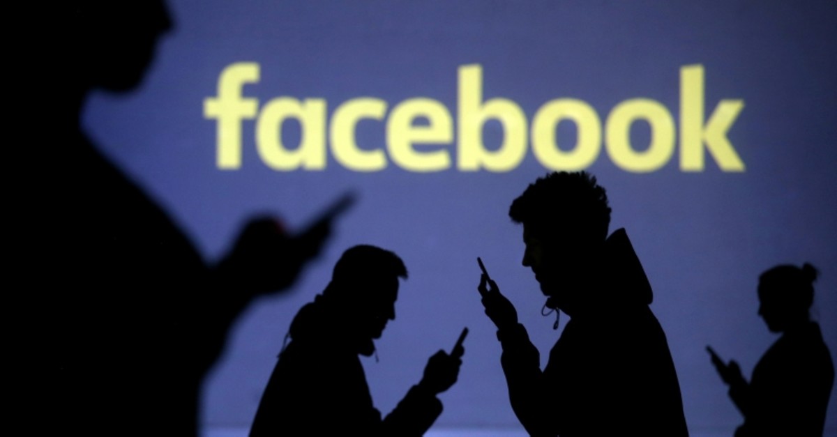 Silhouettes of mobile users are seen next to a screen projection of the Facebook logo in this picture illustration taken March 28, 2018 (Reuters File Photo)