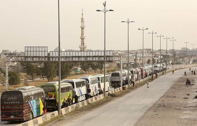 A picture taken on March 22, 2018 shows an elevated view of Syrian opposition fighters waiting by buses at the entrance of Harasta in eastern Ghouta on the outskirts of the capital Damascus (AFP Photo)