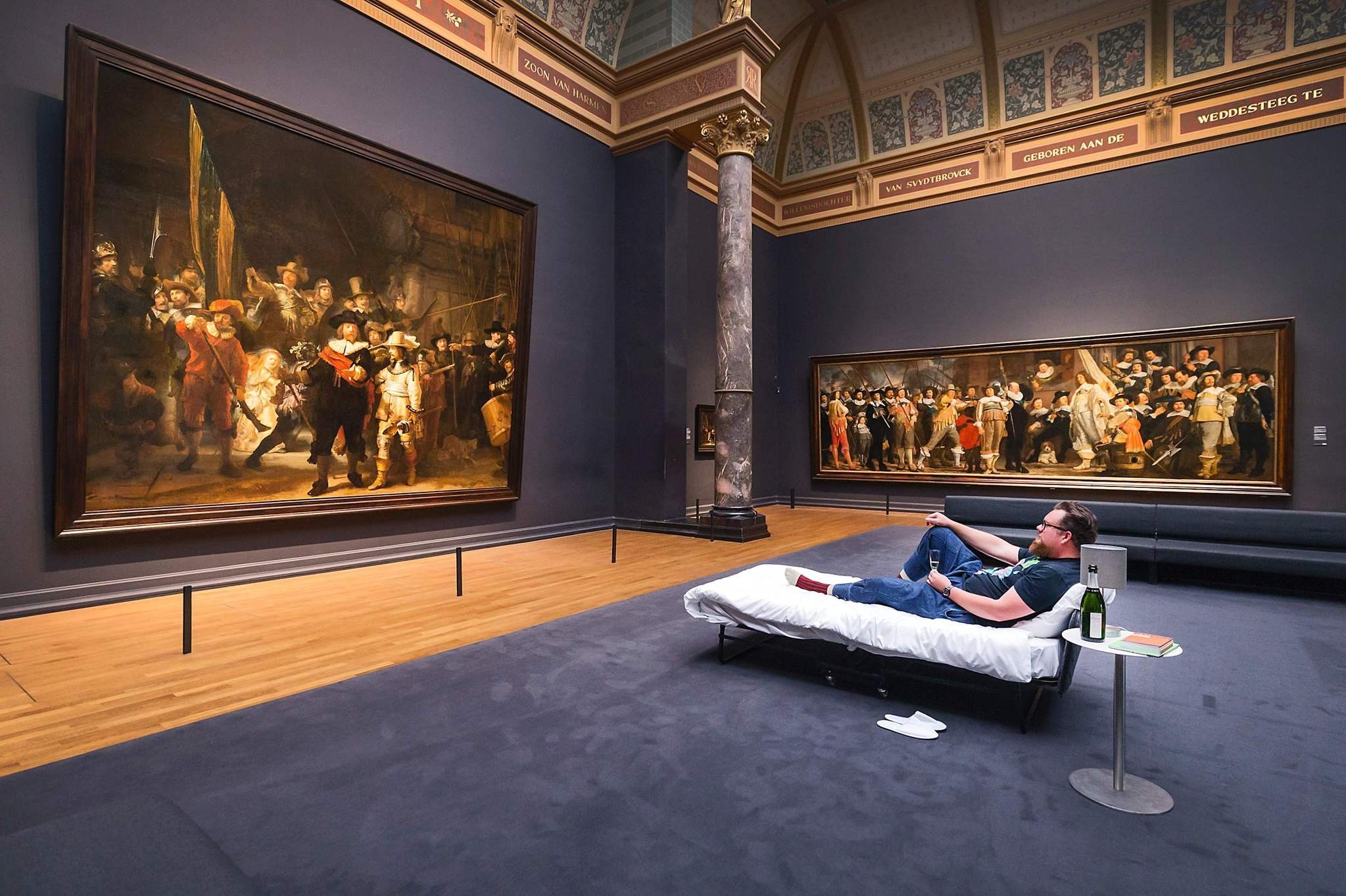 This handout picture released on June 2, 2017 by the Rijksmuseum of Amsterdam shows Stefan Kasper lying in a bed in front of the painting ,The Night Watch, by Dutch painter Rembrandt at the Rijksmuseum of Amsterdam on June 1, 2017. (AFP Photo)