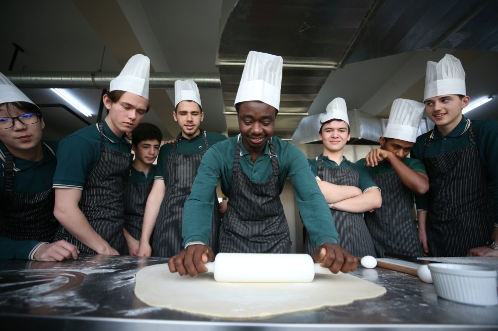 Ghanan student (middle) prepares the traditional dish ,waakye.,